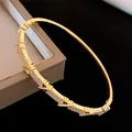 Vue macro d'un bracelet jonc plaqué or avec zircons étincelants et motif en croix - Or