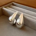 Close-up of minimalist silver metallic teardrop stud earrings placed in a grey velvet box - Silver