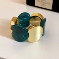 Dettaglio di un bracciale elastico in acrilico marmorizzato verde acqua e metallo dorato. - Verde