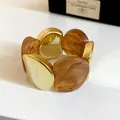 Primo piano del bracciale elastico in acrilico ambrato e metallo dorato grosso. - Caffè Chiaro