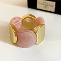 Dettaglio di un bracciale elastico con acrilico rosa marmorizzato e metallo oro. - Rosa