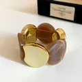 Dettaglio di un bracciale elastico in acrilico e metallo dorato con trama marmorea - Grigio Caffè