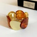 Primo piano di un bracciale elastico retrò in acrilico e metallo dorato, stile vintage - Caffè Scuro