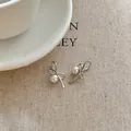 Detail view of Korean style silver ribbon bow earrings decorated with elegant white pearls - Bowknot Pearl Ear Clips / Silver