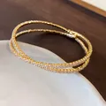 Detailed view of the double-layer crisscross gold bracelet with sparkling cubic zirconia stones. - Double Layer Crossover Open Style / Gold