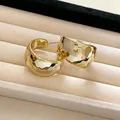 Macro view of minimalist gold hammered C-shaped hoop earrings on a soft jewelry display - Gold