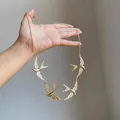 Detailed close-up of a gold-toned metal swallow necklace featuring four bird charms - Gold
