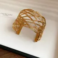 Primo piano di un bracciale rigido intrecciato in maglia dorata in una confezione - Stile 3 / Oro