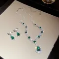 Primo piano del set di collana e orecchini a goccia di smeraldo vintage di lusso con strass - Set Collana E Orecchini (Clip) / Argento (Zircone Verde)