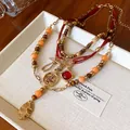Detailed view of multi-layered ethnic beaded necklace with vintage pendants - Gold Orange