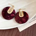 Dettaglio macro di orecchini circolari in acetato bordeaux placcati in oro 18 carati. - Motivo Marmo Rotondo / Perno in argento 925 / Borgogna