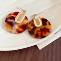 Primo piano di orecchini tondi in acetato tartarugato con perni placcati in oro 18 carati - Motivo Tartarugato Rotondo / Perno in argento 925 / Marrone
