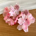 Primo piano dettagliato di eleganti orecchini a fiore in chiffon rosa su sfondo legno - Rosa-Verde