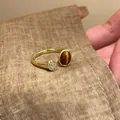 Dettaglio di un anello aperto dorato con occhio di tigre marrone e pietre pavé brillanti. - Stile Disco in Pietra Principale Ovale / Oro