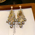 Detail view of elegant tassel earrings featuring zircon studs and faceted glass beads. - Gold-Grey