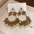 Close-up view of vintage ethnic earrings with pearls, rhinestones and floral motifs - Gold-White
