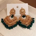Detailed macro view of ethnic style gold chandelier earrings decorated with dark green beads - Gold-Green