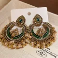 Close-up detail of ethnic vintage drop earrings featuring pearls and emerald green stones - Gold-Green-White