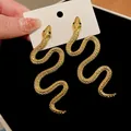 Vue détaillée des boucles d'oreilles serpent dorées avec yeux en gemme verte et écailles - Forme de Serpent / Tige en argent 925 / Or