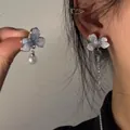 Dettaglio di orecchini floreali asimmetrici con perla e lunga nappa in azzurro chiaro - Stile Perno in Argento / Argento-Blu