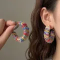 Primo piano di orecchini a cerchio geometrici avvolti in filati colorati vivaci e unici - Forma a C Perno in Argento / Oro-Rosa