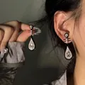 Dettaglio delle eleganti orecchini a goccia neri con cristalli indossati da una modella asiatica - Stile Perno in Argento / Nero