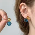 Dettaglio ravvicinato di orecchini a lobo circolari traslucidi blu e gialli. - Stile Perno in Argento / Blu-Giallo