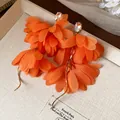 Dettaglio orecchini a fiore in chiffon arancione con borchie di cristallo e catene d'oro - Arancione