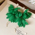 Dettaglio ravvicinato di orecchini a fiore in chiffon verde con strass eleganti - Verde
