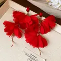 Primo piano di eleganti orecchini a fiore in chiffon rosso con pietre preziose rosse - Rosso
