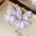 Eleganti orecchini a fiore in chiffon bianco con strass trasparenti in vista ravvicinata - Bianco