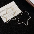 Primer plano detallado de aretes de aro con forma de estrella en tela negra. - Plateado