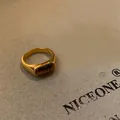 Detail shot of a retro gold-tone ring with brown tiger eye stone on textured paper. - 17# Ring-Gold-Rectangle Stone