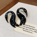 Primer plano de pendientes de cisne en esmalte negro con lunares blancos y oro - Negro