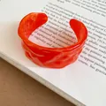 Detailed view of the orange marbled texture on this stylish wrinkled open cuff bracelet. - Orange