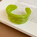 Macro view of a lime green resin cuff bracelet featuring a unique textured pleated design - Green