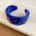 Detail view of a deep blue resin cuff bracelet with a unique wavy marbled texture. - Blue
