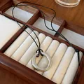 Gros plan d'un collier pendentif circulaire argenté dans un coffret en bois. - Pendentif rond / Argent