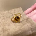 Dettaglio di un anello vintage a sole con pietra occhio di tigre su lino naturale. - Stile girasole / Pietra occhio di tigre sintetica / Oro
