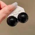 Close-up of large glossy black round stud earrings with 925 silver needle - Black