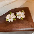 Close-up detail of vintage floral stud earrings with pearly petals and green leaves - French Enamel Flower Style (21# Silver Post)