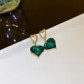 Elegant gold-tone stud earrings featuring faceted emerald green heart-shaped crystals - Hollow Heart Drop / Green