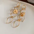 Elegant gold hollow tassel earrings with twisted geometric links on white tray - Oval Hollow Tassel Earrings (45#) / Gold