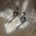 Detailed macro of ornate silver dangling earrings with pear-cut clear stones on white knit. - Water Drop Style / 925 Silver Needle / Silver