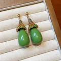 Close-up of vintage drop earrings with colorful rhinestones and green resin water drops - Green