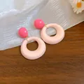Primo piano di orecchini a cerchio in acrilico con perla rosa su legno e stoffa - Rosa