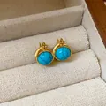 Primer plano detallado de pendientes de aro vintage dorados con piedras redondas de resina - Estilo de aro / Pendiente Huggie - Azul