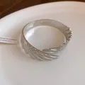 Close-up detail of the intricate silver feather pattern on this twisted metal cuff bracelet - Feather Style / Silver