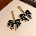 Vue rapprochée d'élégantes boucles d'oreilles pendantes nœud en strass noir et blanc - Or-Noir