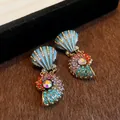 Nahaufnahme farbenfroher, mit Strass besetzter Muschel-Ohrringe in Vintage-Gold Optik - Ohrringe / Silbernadel / bunt